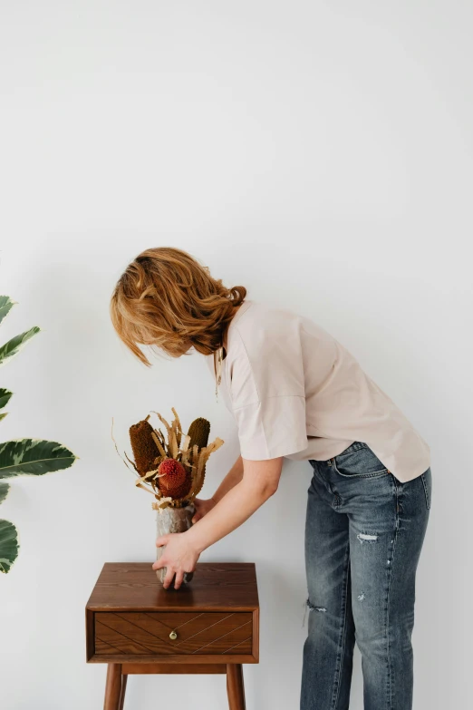 woman leaning over looking at flowers in vase