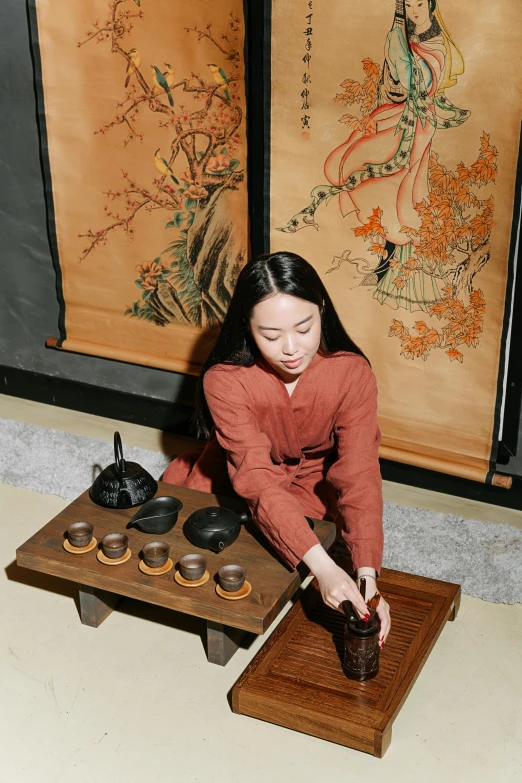 a young woman in red jacket standing at tray and serving tea