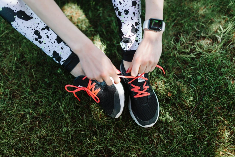 a person's shoes in the grass tying their running rope