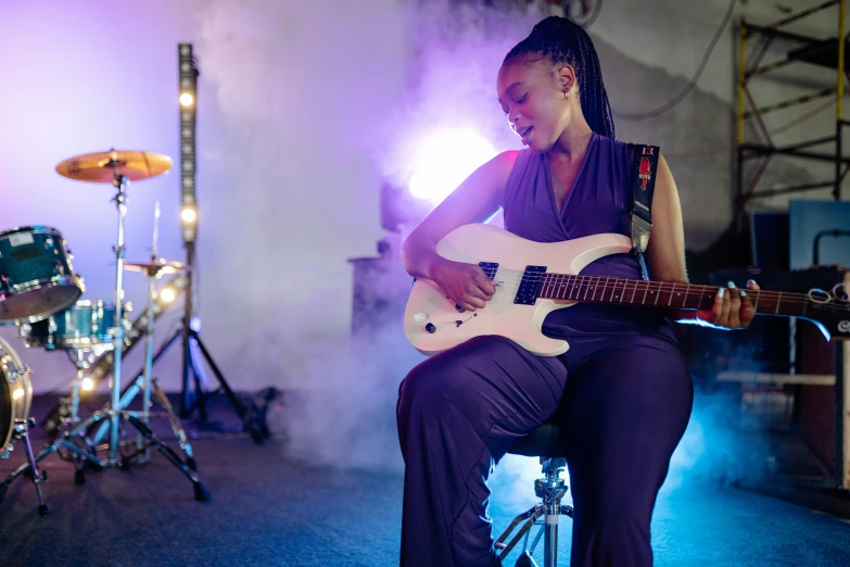 a woman in purple playing a white guitar