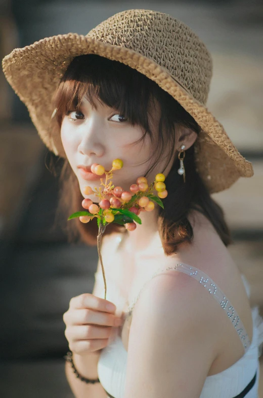 a beautiful young woman in a straw hat smelling the flowers