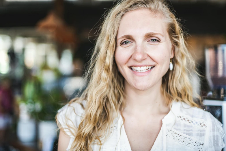 a woman with long blonde hair and blue eyes is smiling