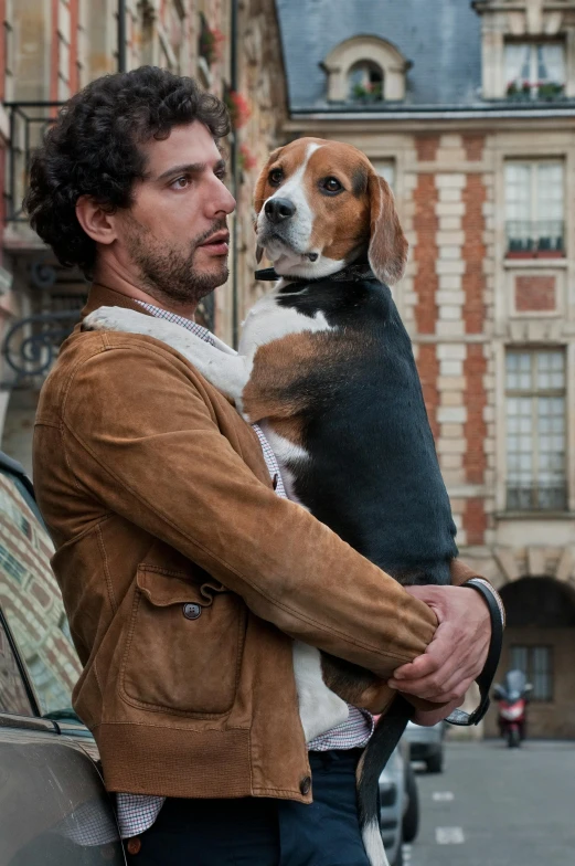 man wearing brown leather jacket holding dog in car