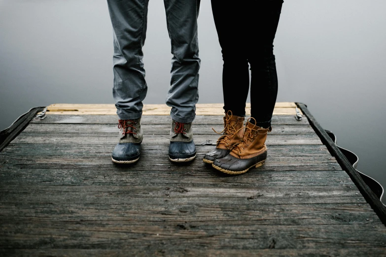 a couple stands on a pier holding hands