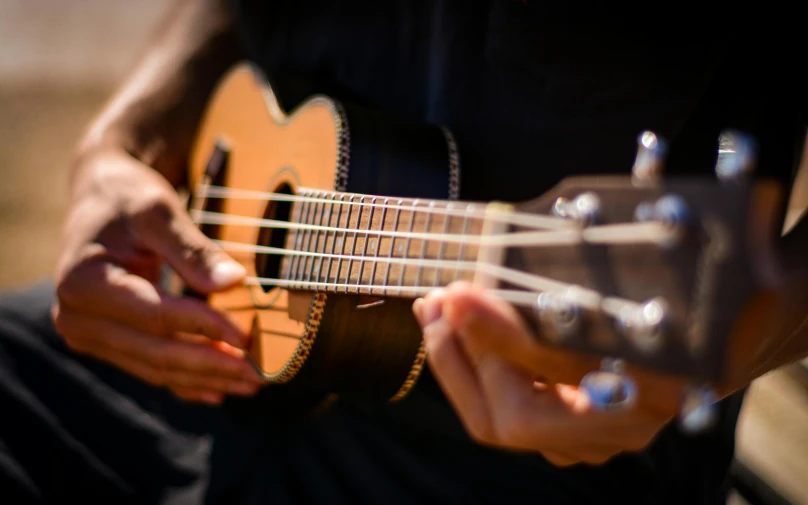 the hands of a person holding an acoustic guitar