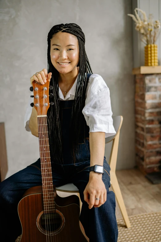 a young woman with dreadlocks holding an acoustic guitar