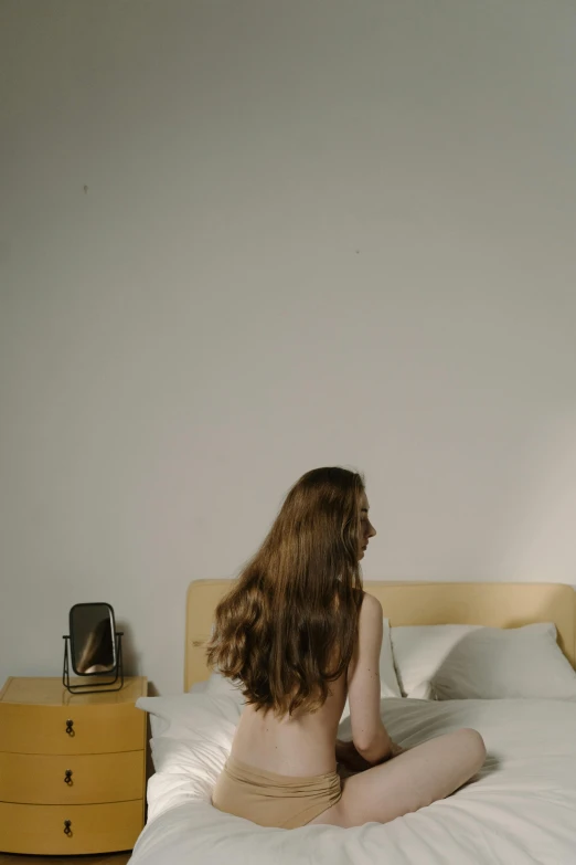 the young woman is sitting on the bed