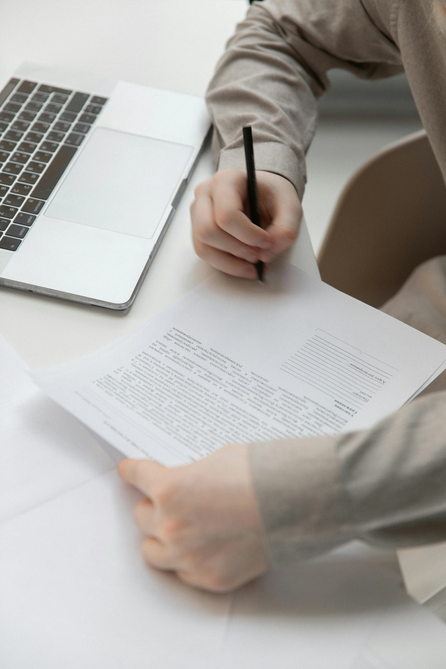 man filling out form with pen and laptop nearby