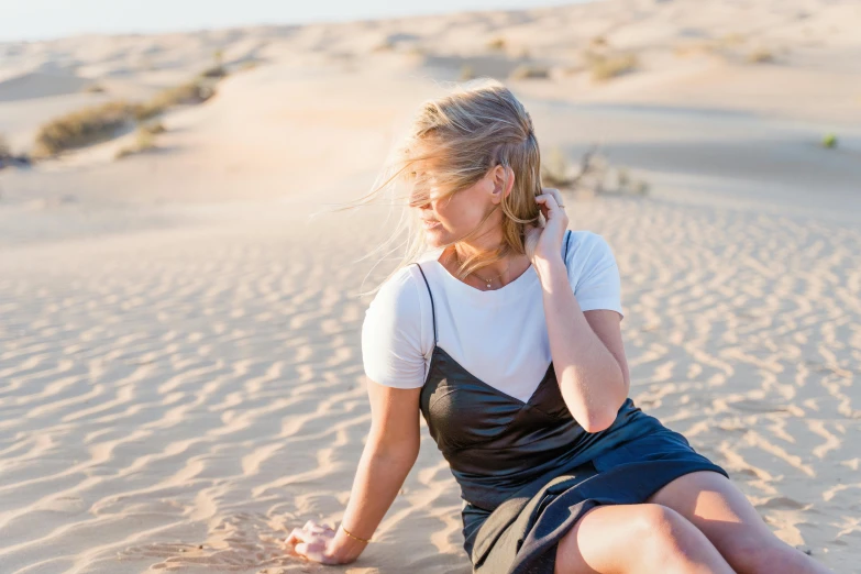 woman sitting in sand and talking on phone