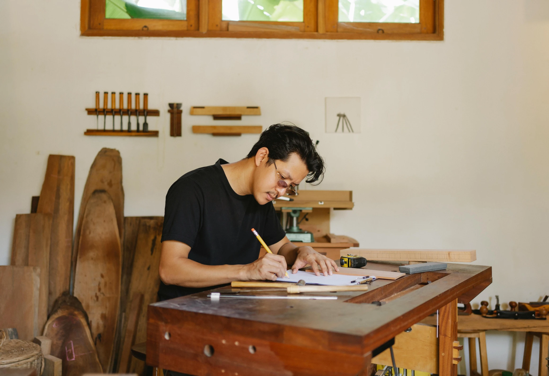 a man sitting at a table while working with wood