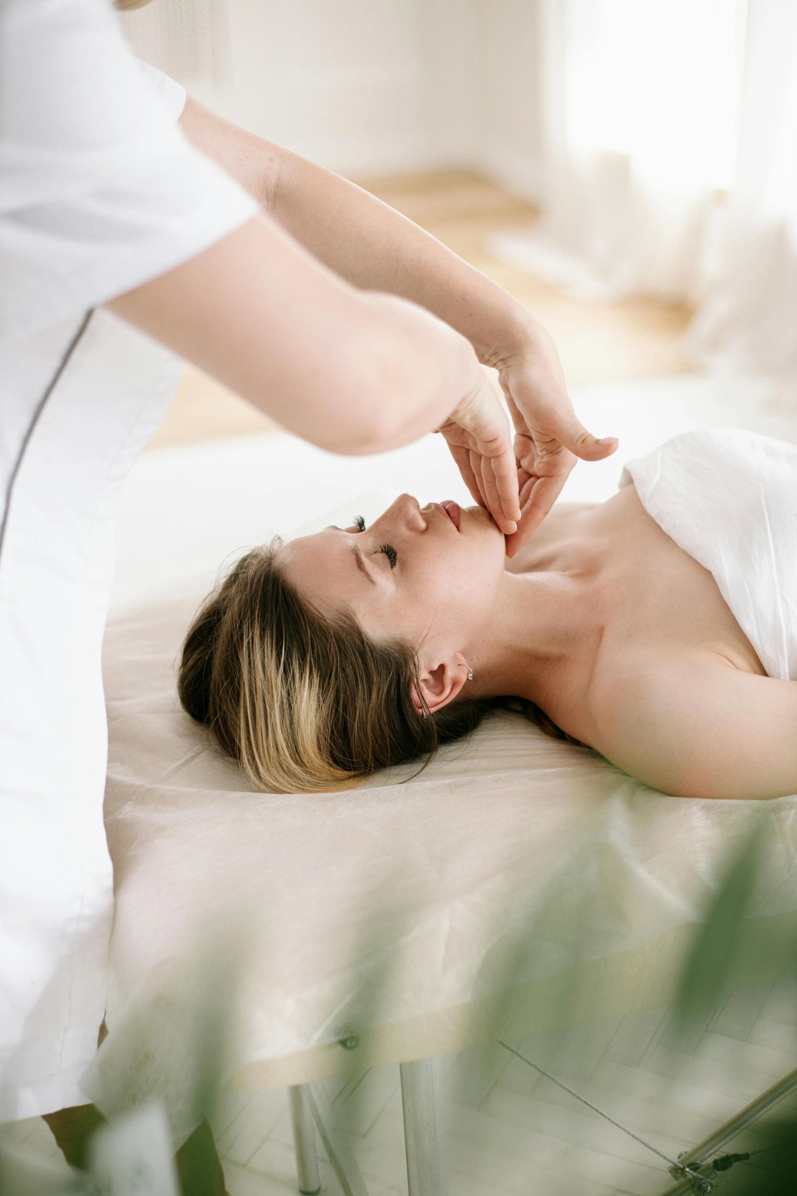 a woman lays on her stomach as someone reaches down toward her back