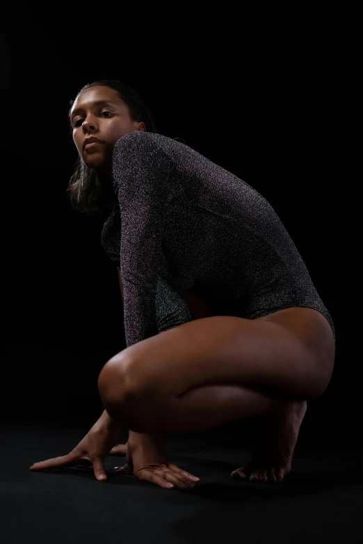 a woman kneeling on a dark surface posing