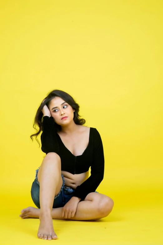 young woman sitting cross - legged on a yellow background