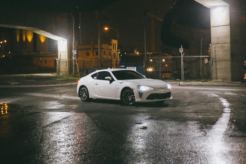 a white sports car parked in the rain on a street