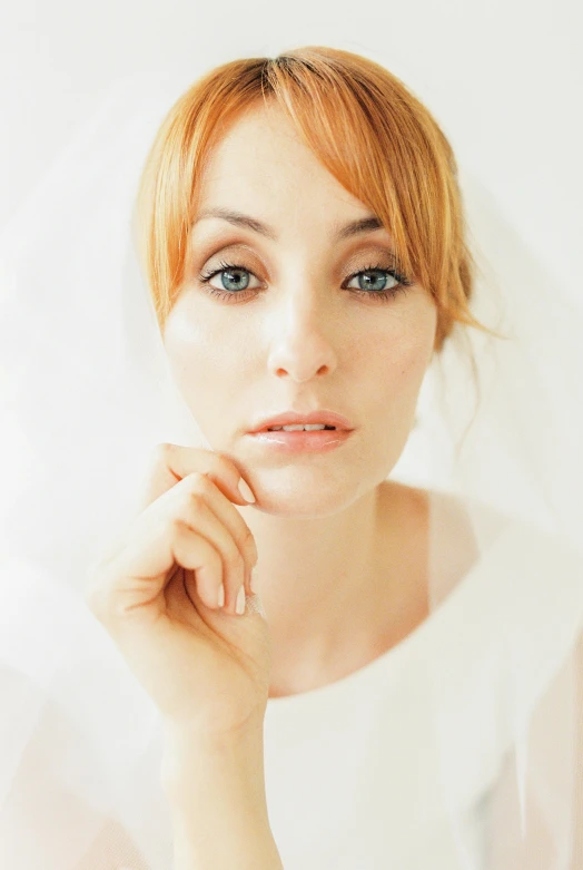 a young woman in white with her hands near her face