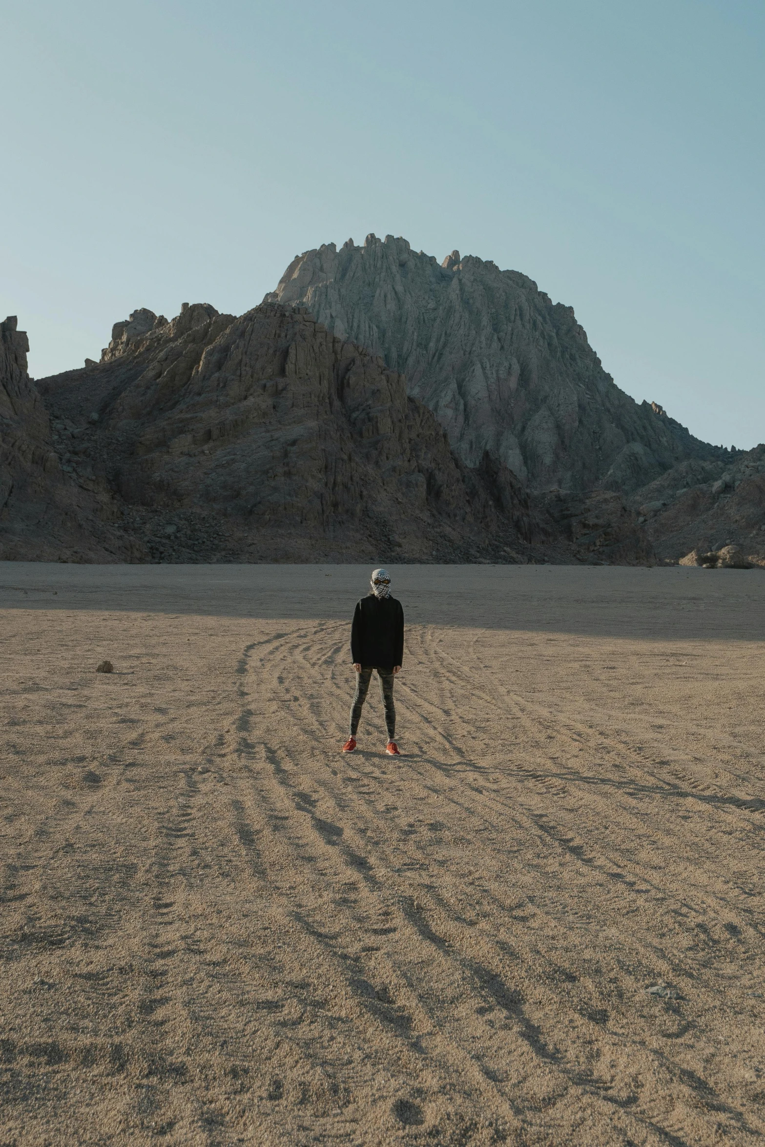 man standing in desert looking towards mountains