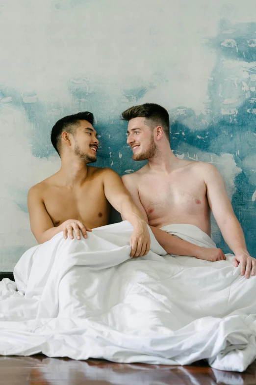 two gay men sitting on the bed having conversation