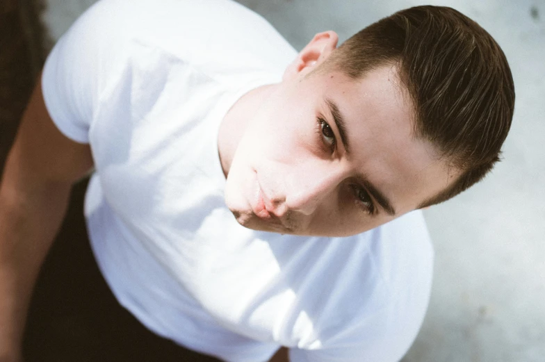 a young man posing for the camera, he wears a white shirt