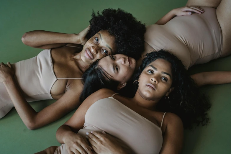 three girls lie on the ground in different outfits