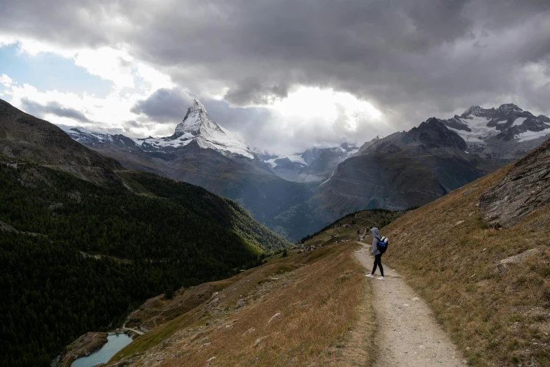 two people hiking along a trail in the mountains