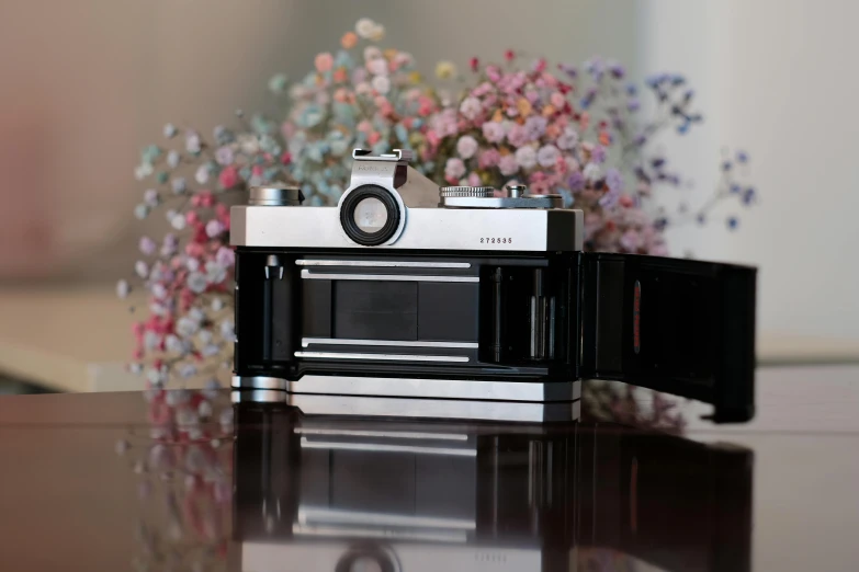 a camera with flowers in the background sitting on a table