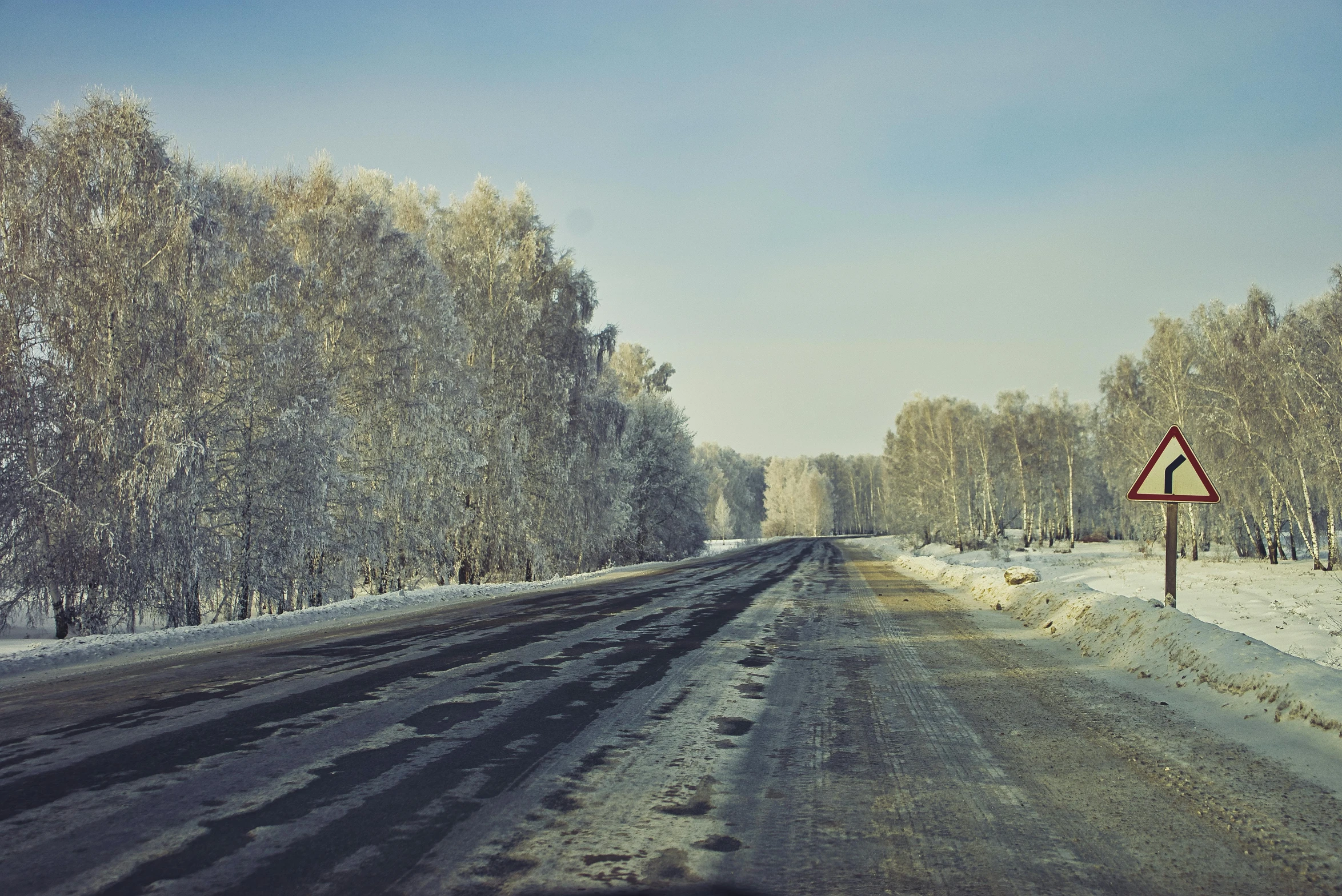 a snowy road that has a sign on it