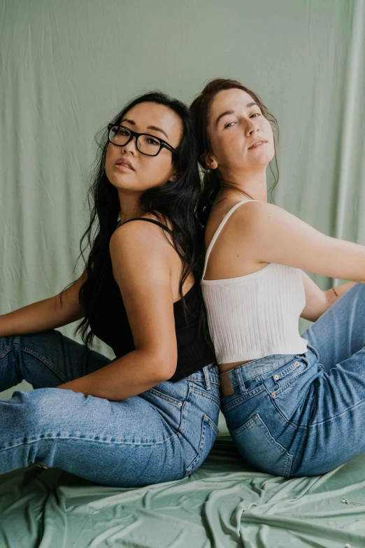 two young women are sitting on a bed together