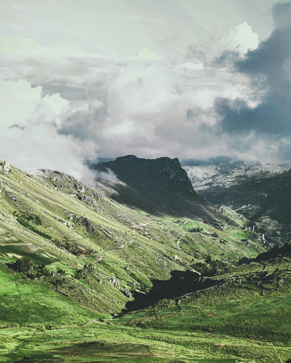 a mountain range with green grass and a mountain