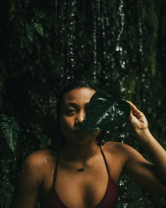 a woman holding a large leaf up to her face