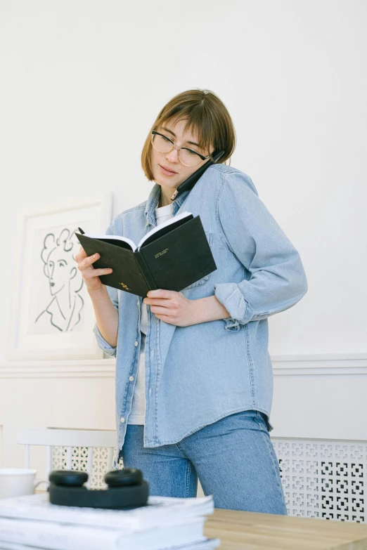 a woman reads from her book as she sits in front of books