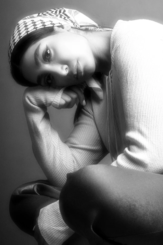 black and white pograph of young lady with head scarf laying on bench