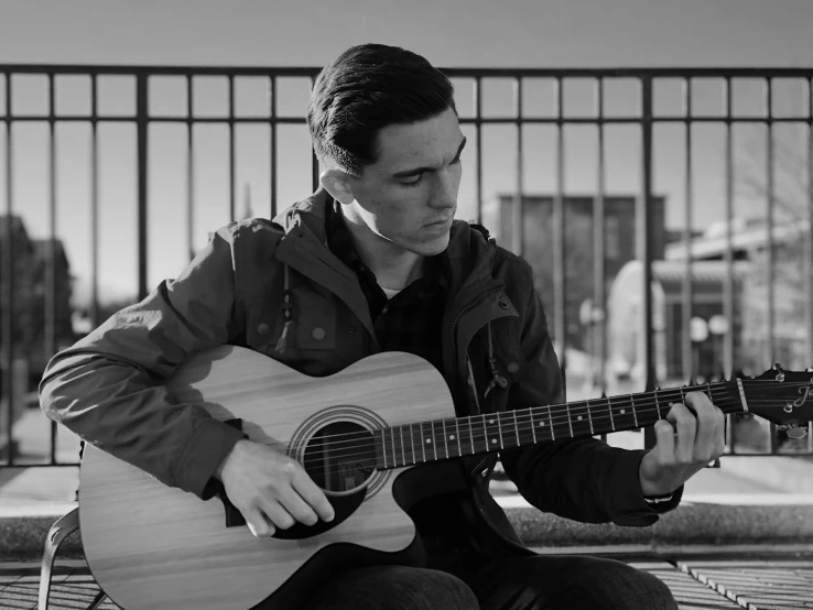 a person holding a guitar sits on a bench