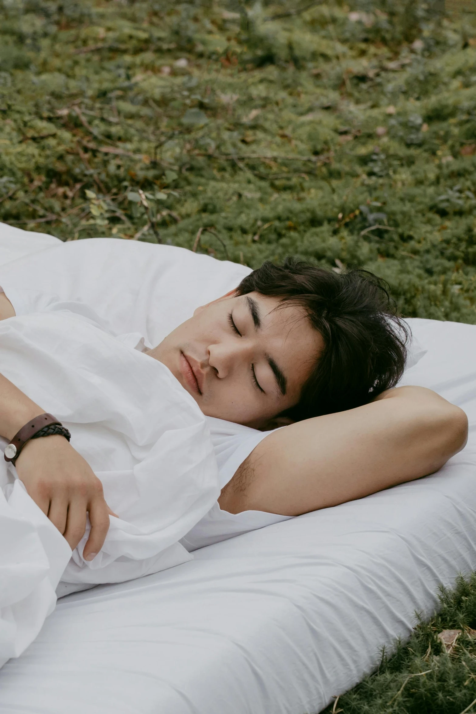 a young woman laying on top of a white mat in a field