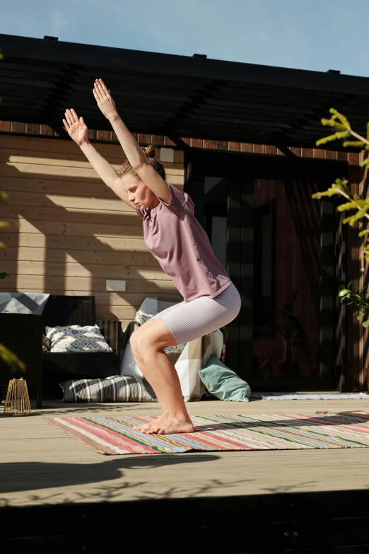 a woman balances on her yoga mat outside