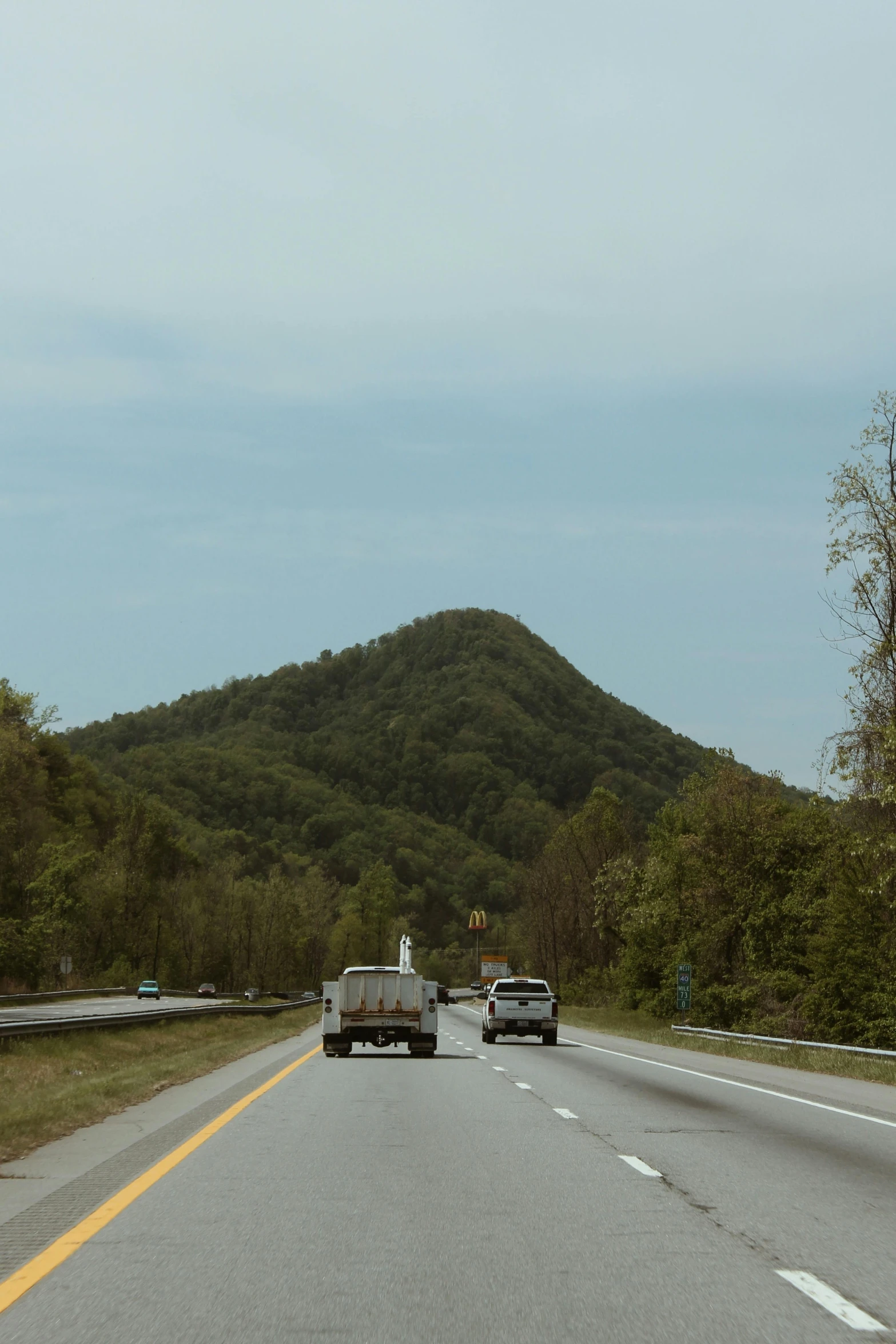 a highway with two vehicles on the side, trees in the background