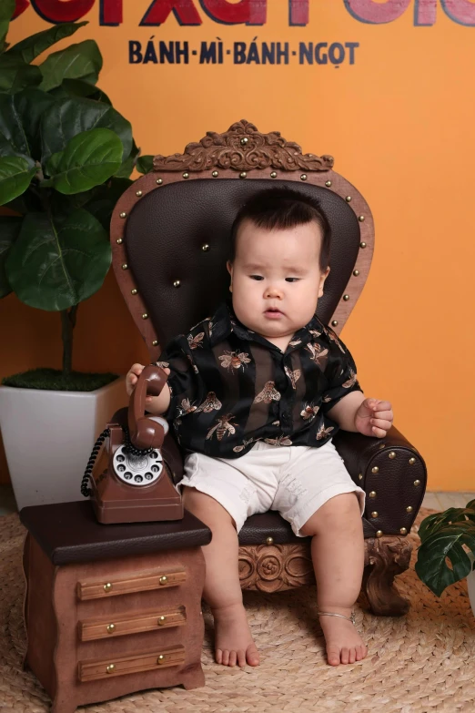 the small baby sits in a chair with an old fashioned toy on top