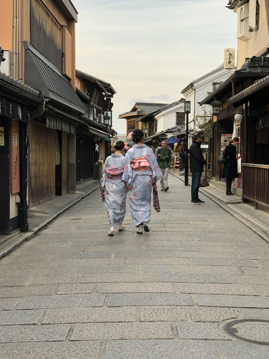 some people in kimono walking in an asian alley
