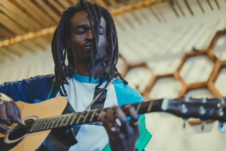 a person with dreadlocks on playing a guitar