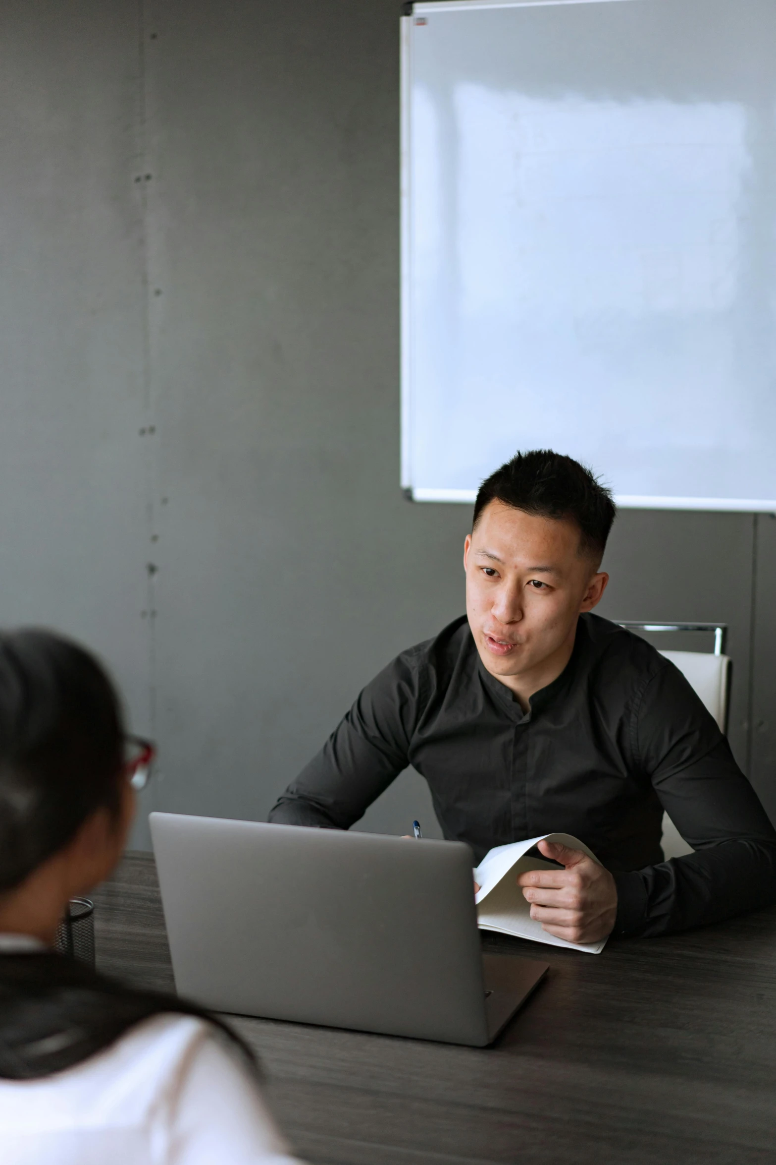 an asian man works on a laptop in an office