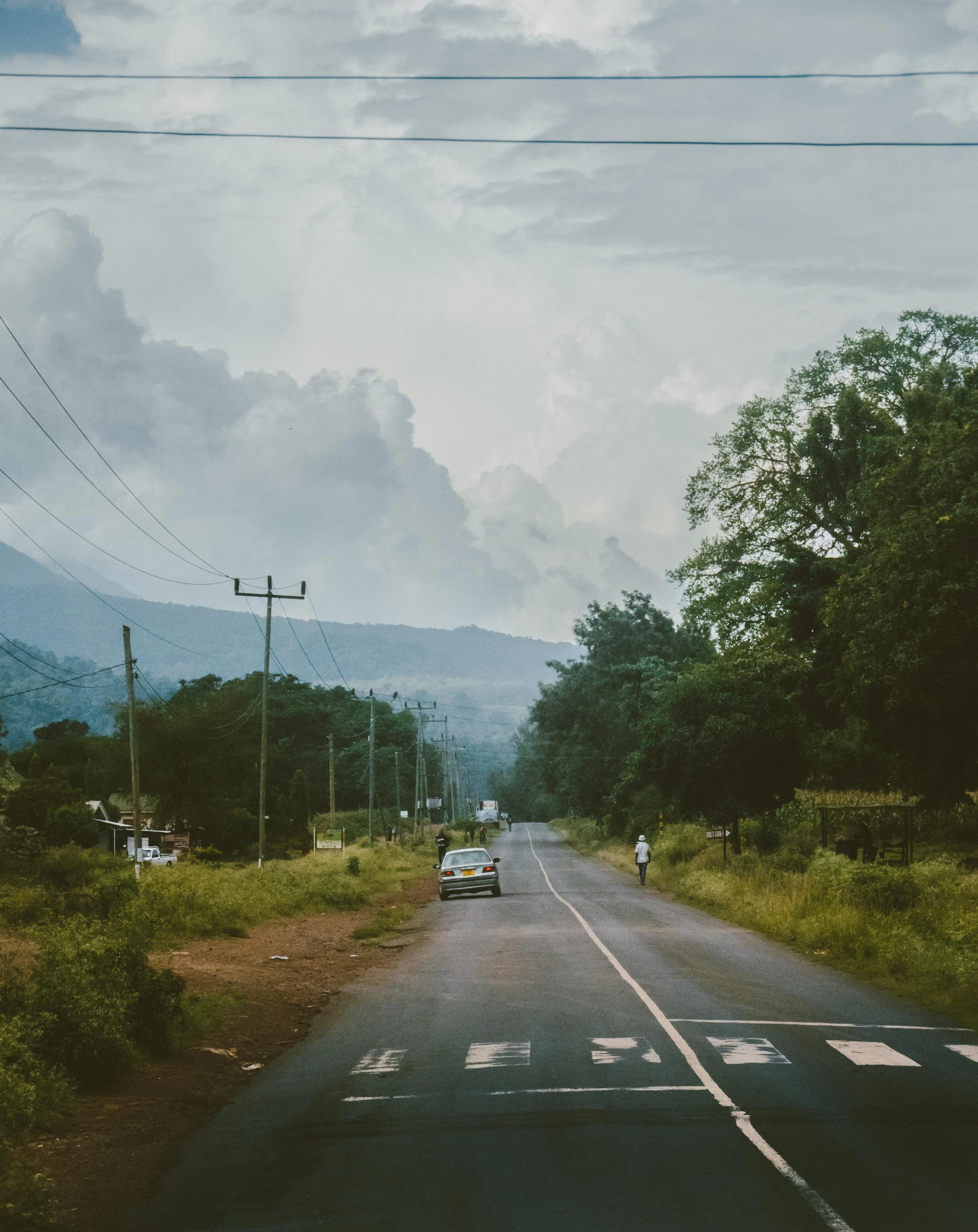 the car is driving down the narrow road near mountains