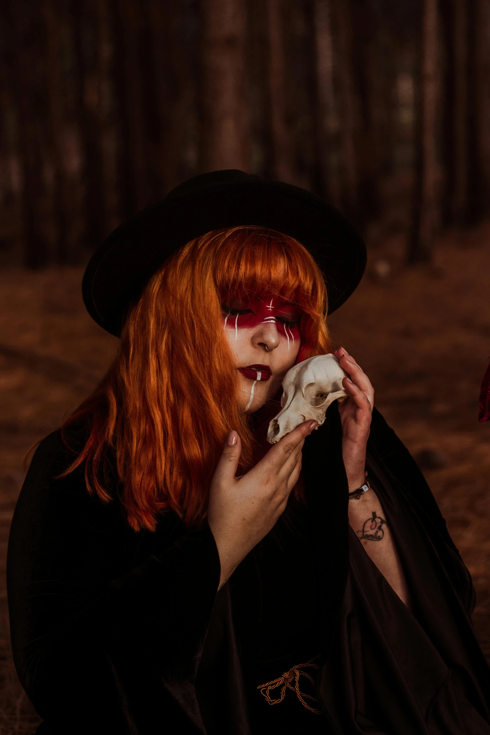 a red - headed woman with glasses, a hat and a coat on is holding a skull in her hands