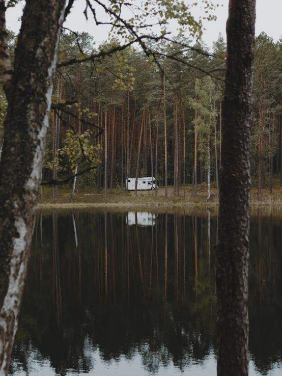an rv sits in the woods near a lake