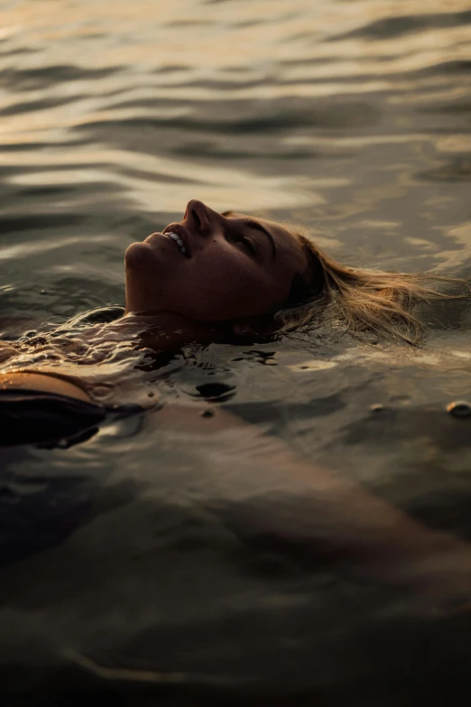 the girl swimming in the lake has her head turned back