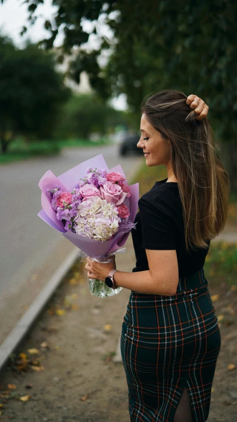 a girl holds a bouquet of flowers and looks off to the side