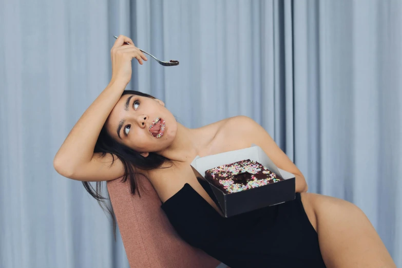 the young woman is holding up a box and eating a donut