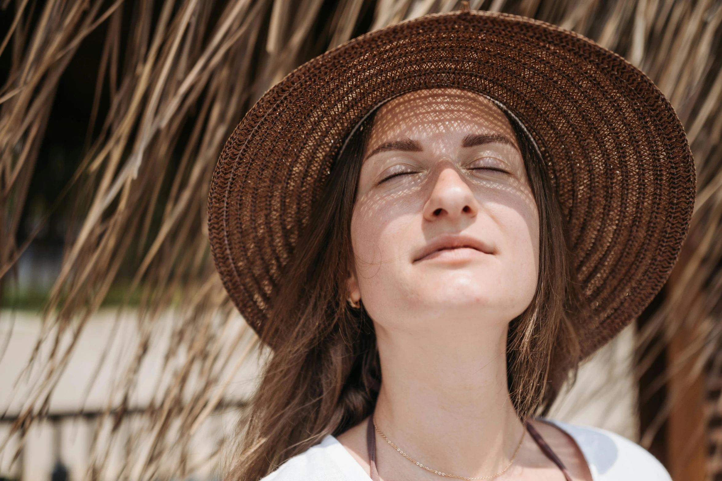 a woman wearing a straw hat is standing under a umbrella