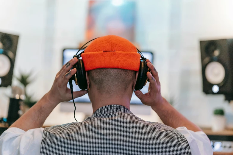 a man wearing headphones and an orange knit cap is listening to music