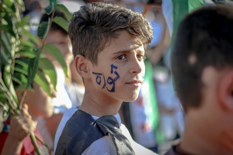 boy with black and white face paint near green leaves