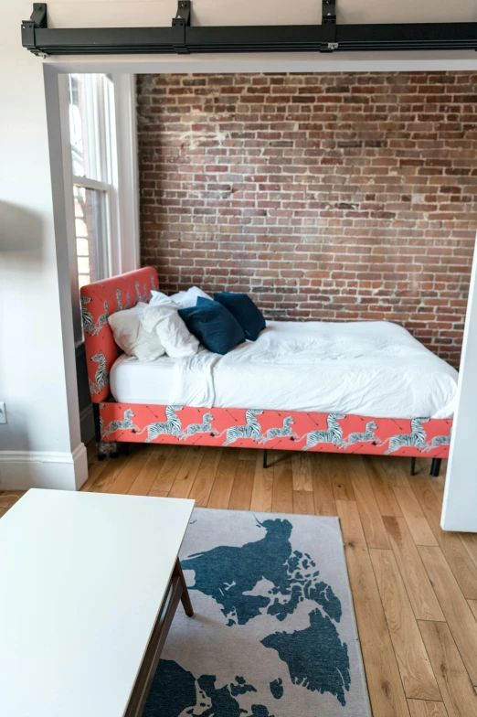 a bedroom with a bed, dresser and brick wall