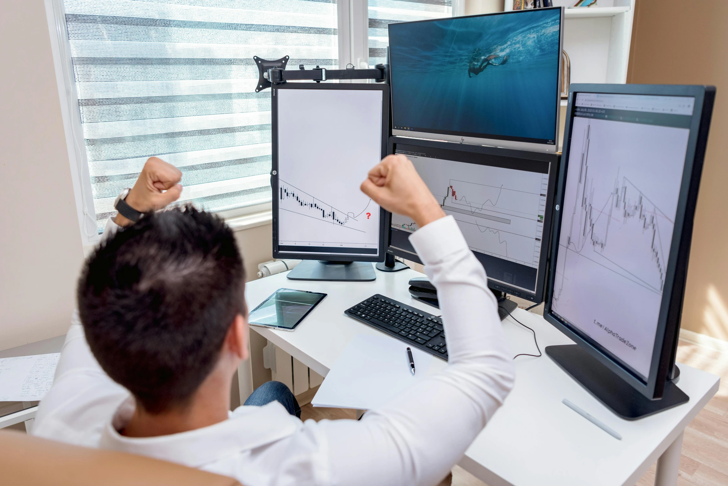 a man sitting at a desk holding up two monitors